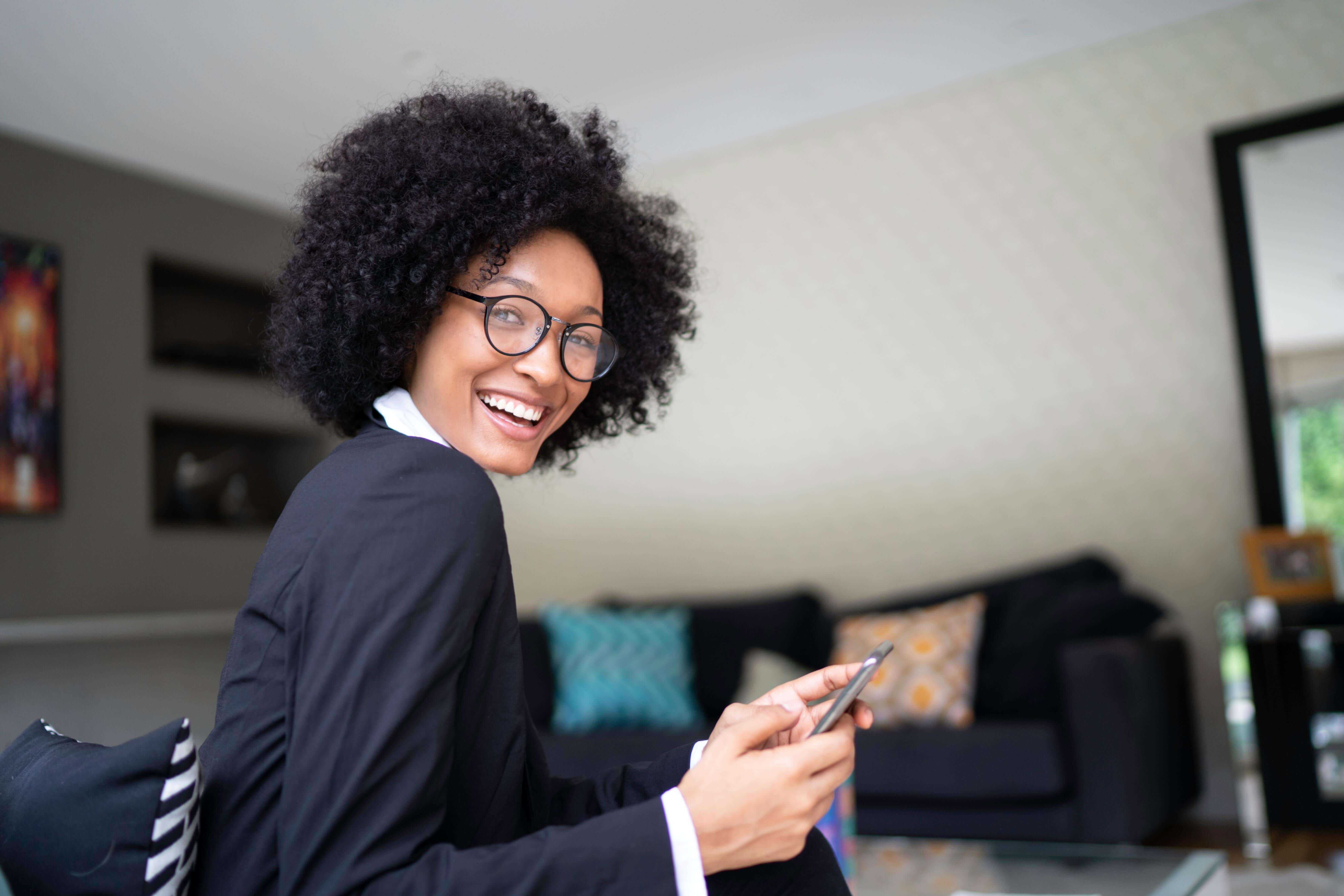 Smiling professional woman using phone, embodying successful leadership development at The Humphrey Group.