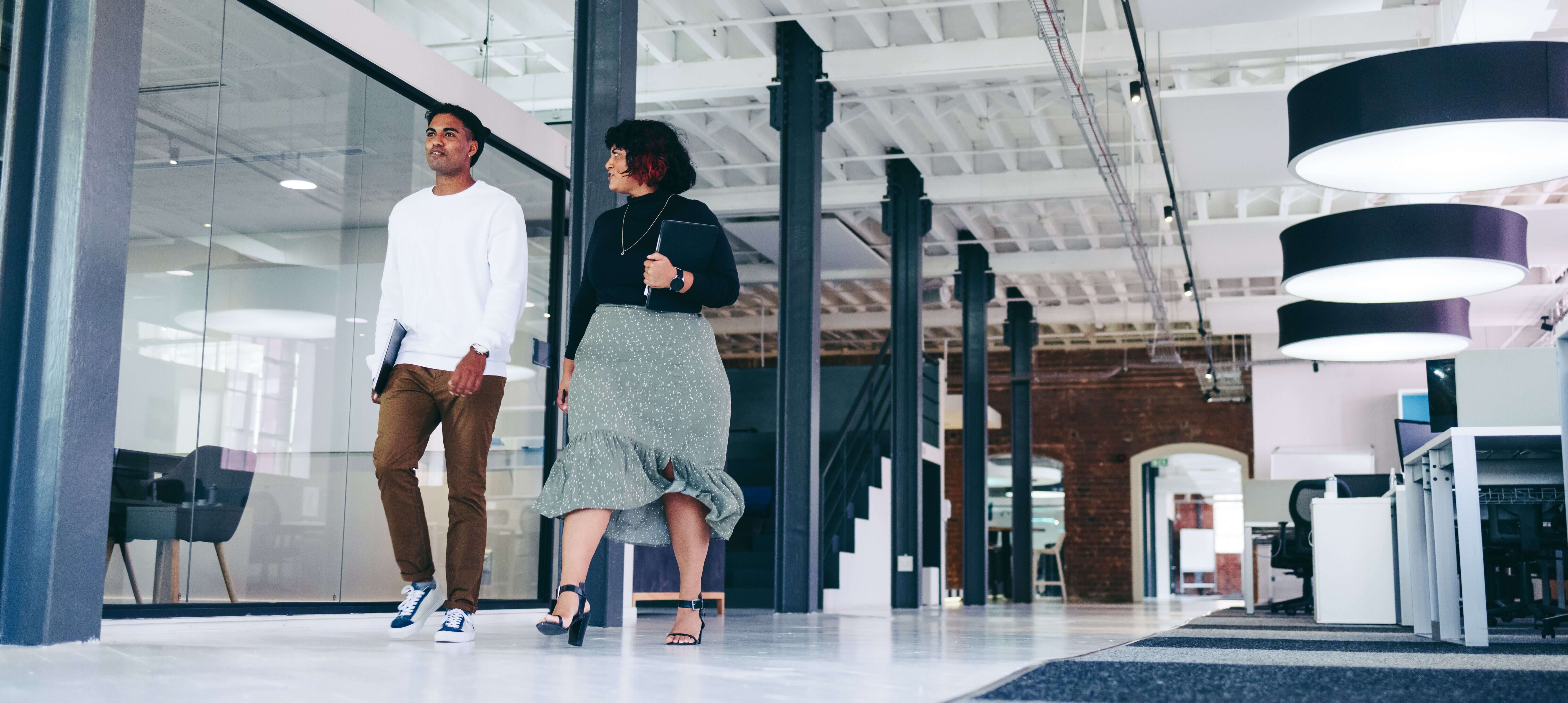 Two ethnically diverse individuals having a walking meeting demonstrating Inclusive Leadership skills. 