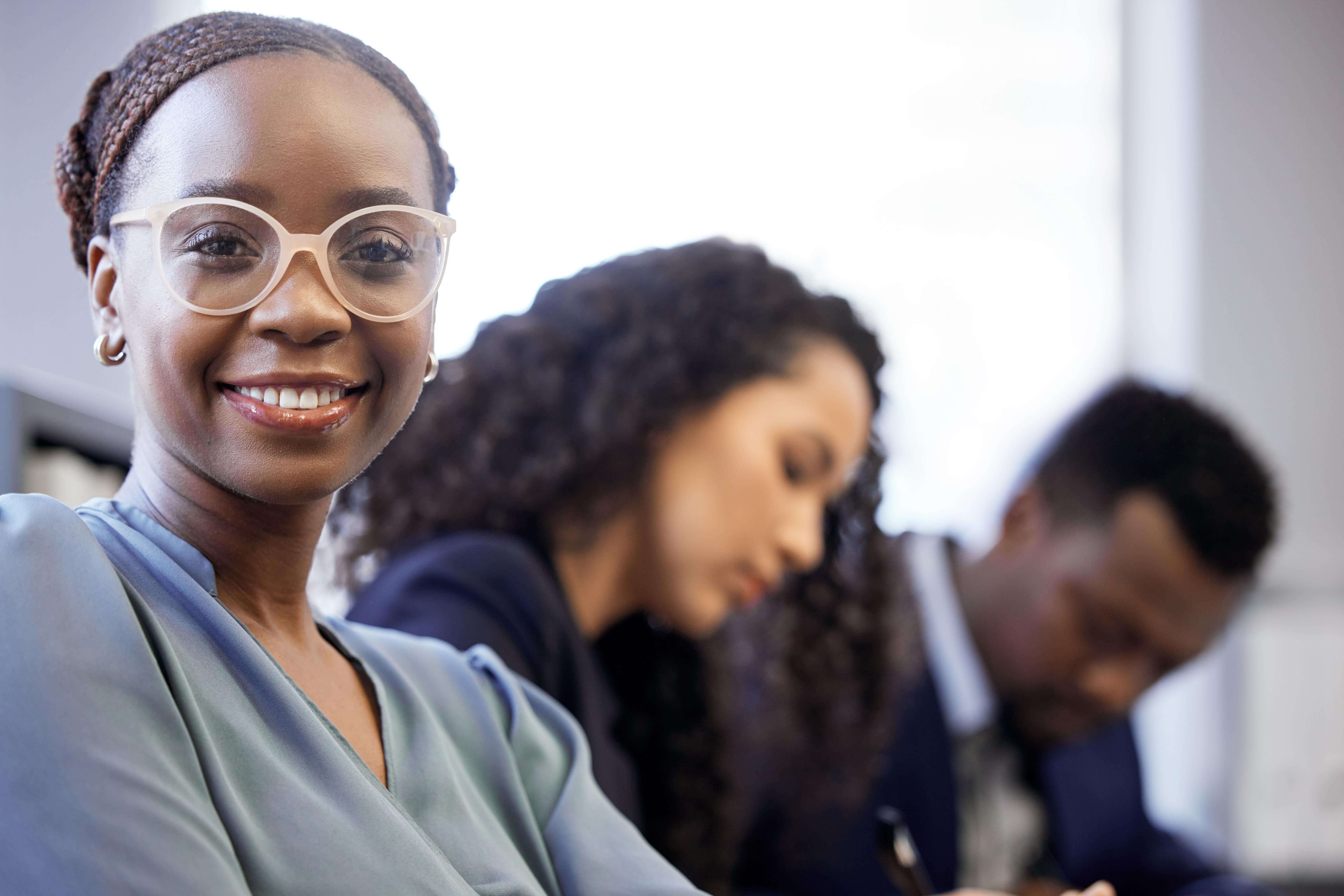 Image featuring a diverse group with a woman at the forefront, smiling, representing 'Inclusive Leadership™' and workplace diversity.