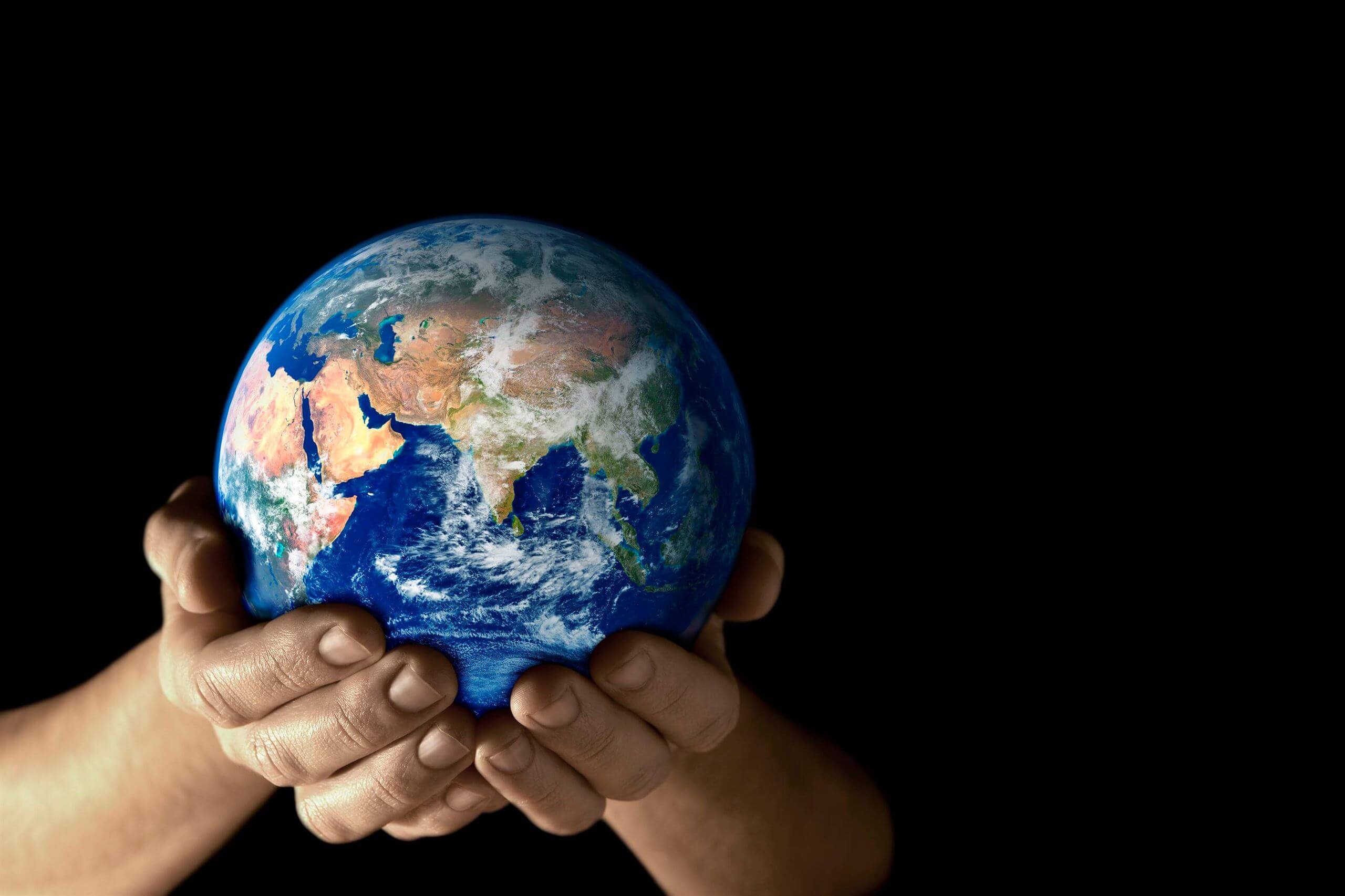 Hands cradling a miniature Earth, symbolizing commitment to the UN's Sustainable Development Goals for a better, sustainable future.