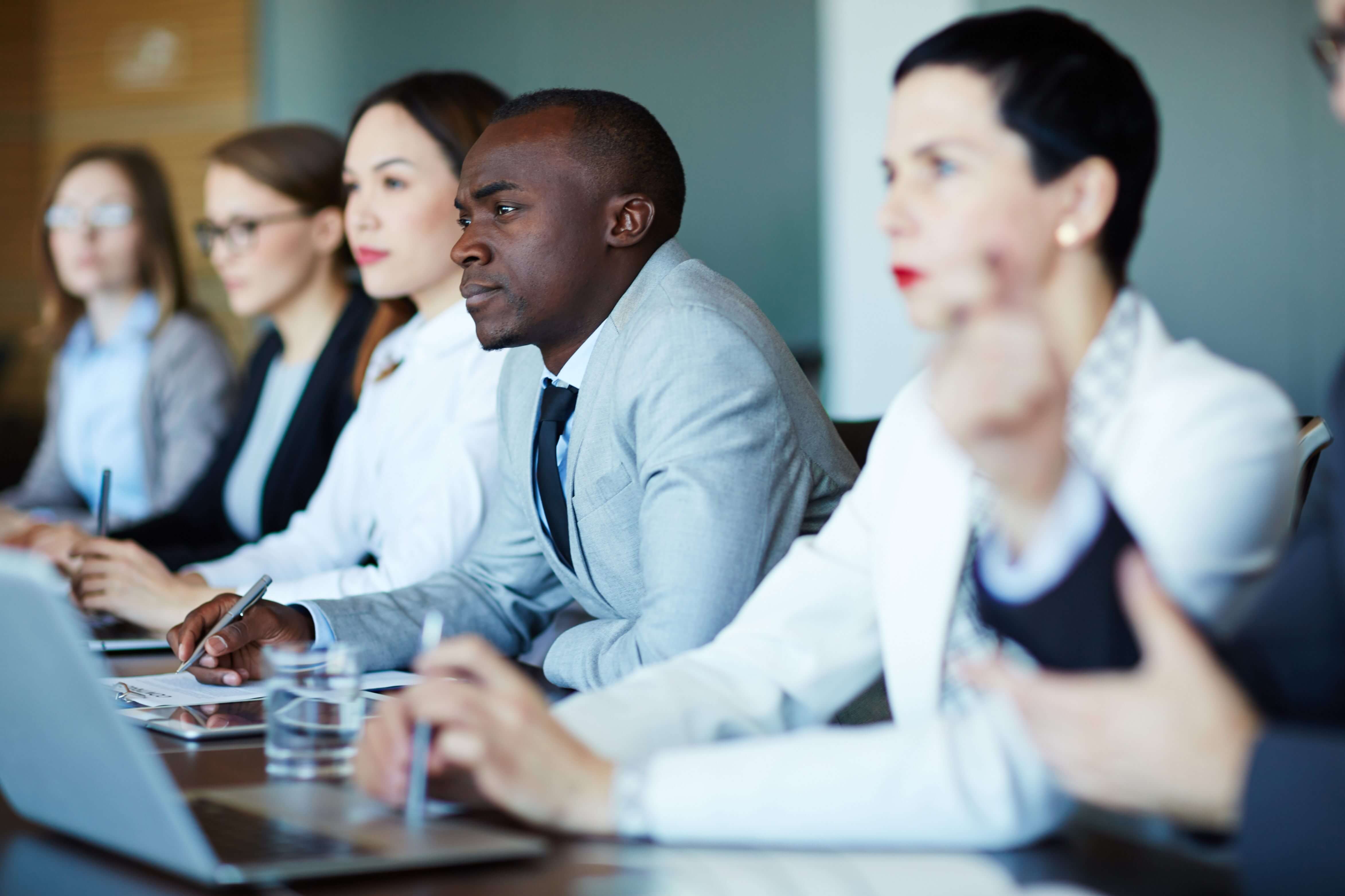 Diverse group of LGBTQ2+ leaders at a meeting, engaged in leadership communication development within Proud to Lead®.