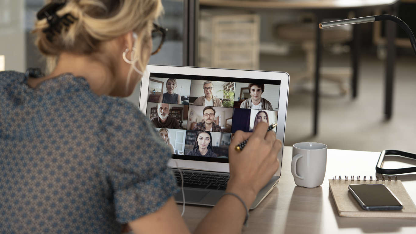 Image of a woman attentively engaging in a virtual call with a group, depicting 'Communicating in a Hybrid World™' and modern team interaction